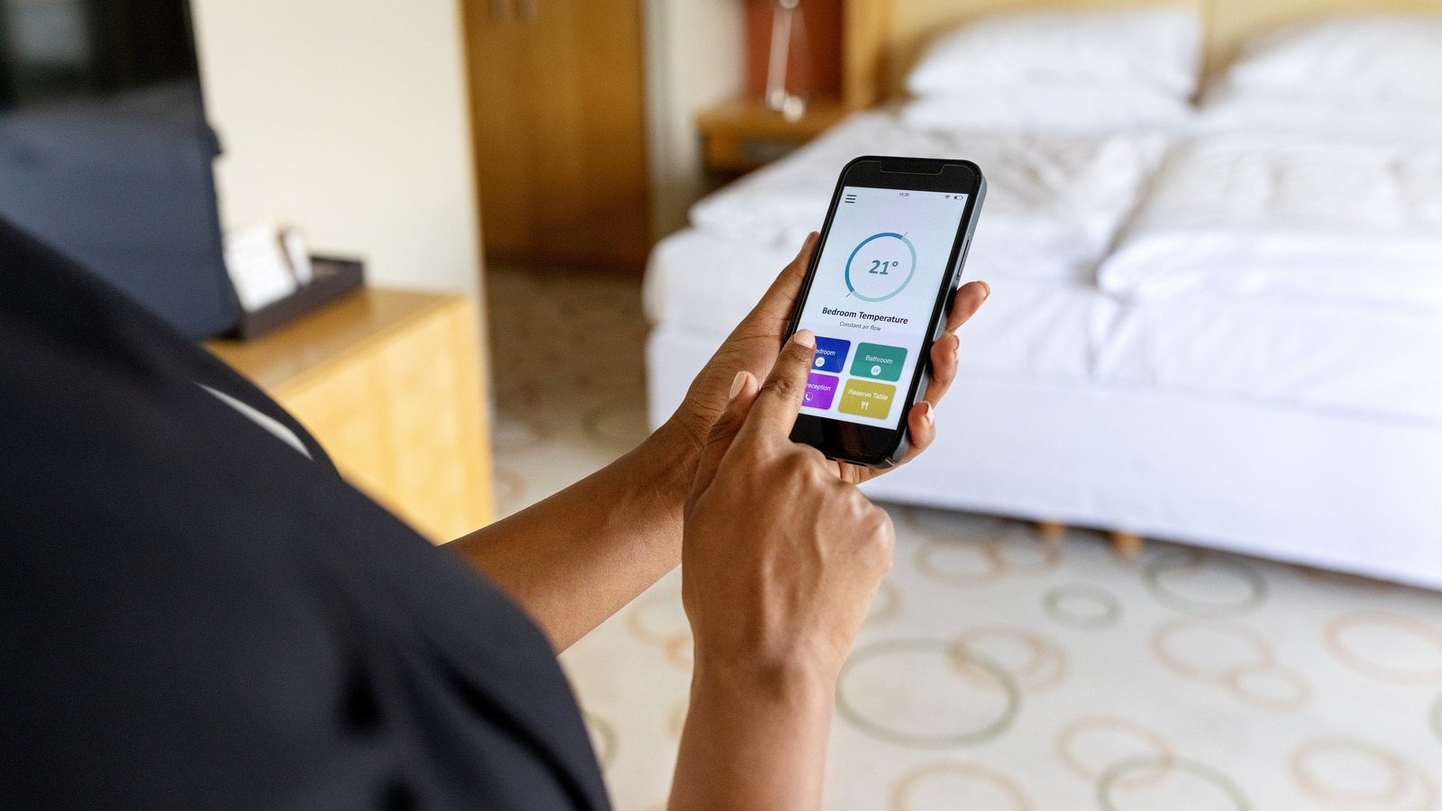 Close-up view of a woman adjusting her hotel room air conditioner with a smart phone app.