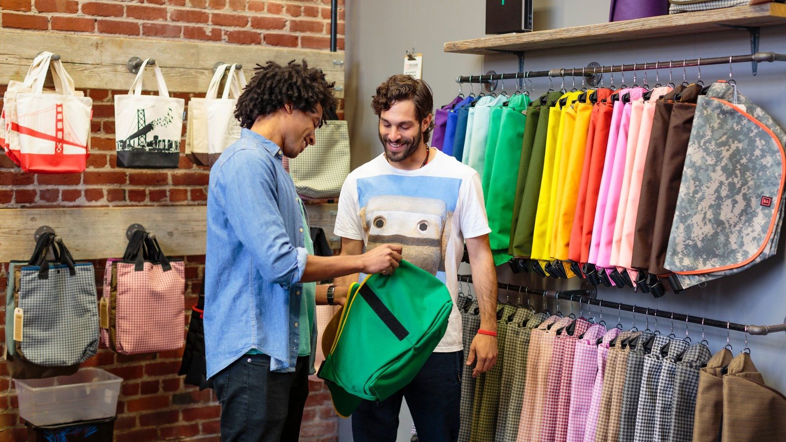 Low angle view of customer and employee inspecting backpack in hip store.